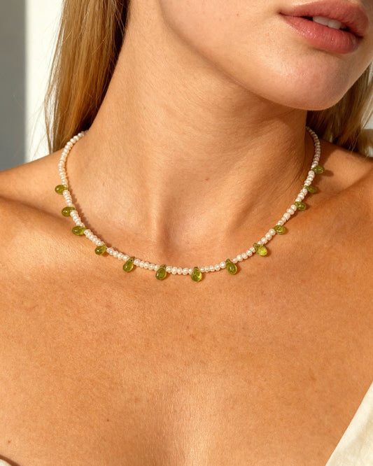 Woman wearing a pearl delicate necklace and peridots